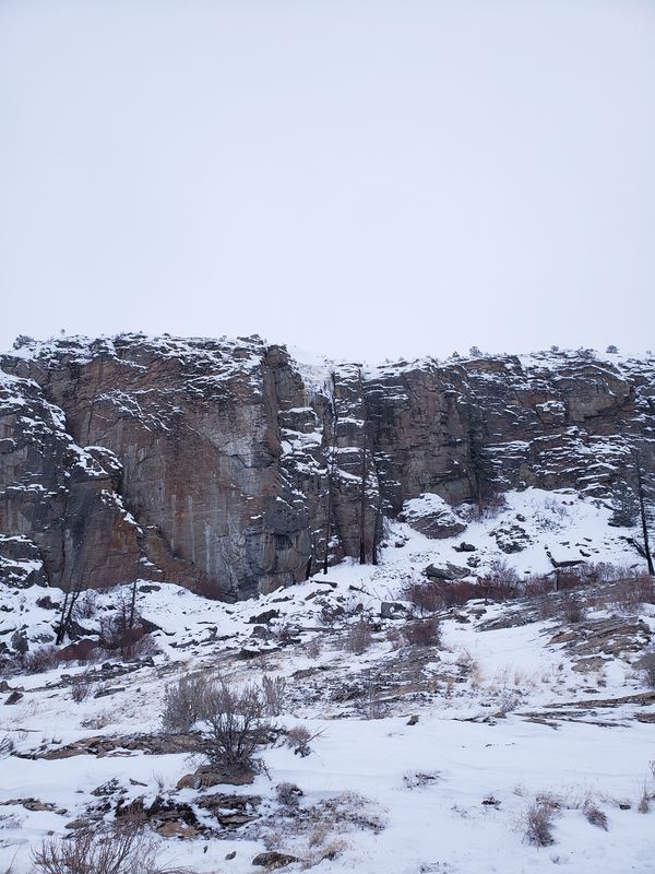 Snow-dusted gneiss cliff face at McLaughlin Canyon with fracture lines visible through a thin winter dusting